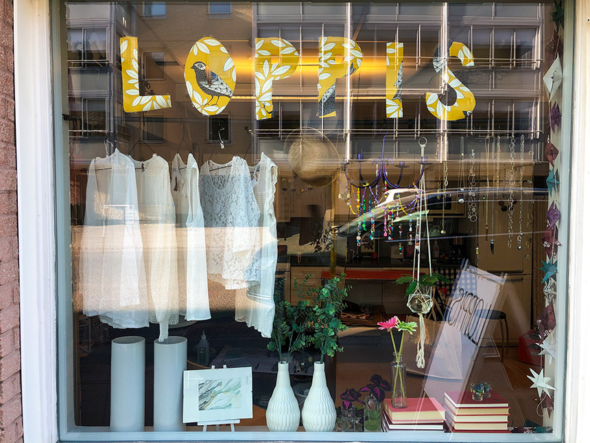 Ett skyltfönster med gula utklippta bokstäver som bildar ordet loppis.